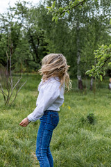 Young woman resting in the park, rejoicing and dancing. The wind develops the hair