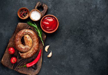 grilled spiral sausage with spices on a cutting board on a stone background with copy space for your text