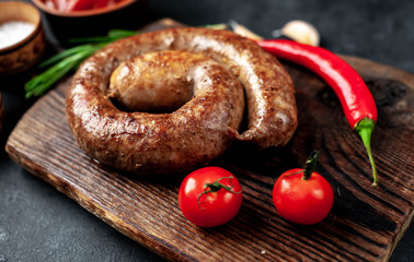 grilled spiral sausage with spices on a cutting board on a stone background