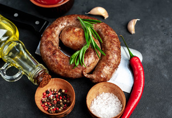 grilled spiral sausage with spices on a meat knife on a stone background 
