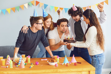 Happy Birthday party. A group of friends with a cake wishes the man a happy birthday