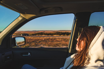 woman sitting in car looking at road. sunset time