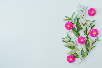 Flat lay frame of flowers and green leaves on a green background