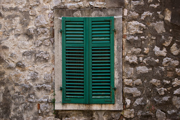 Fototapeta na wymiar A window closed by wooden shutters-blinds green colour