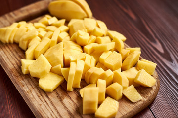 peeled sliced raw potatoes on a wooden board. Preparing vegetables for cooking.