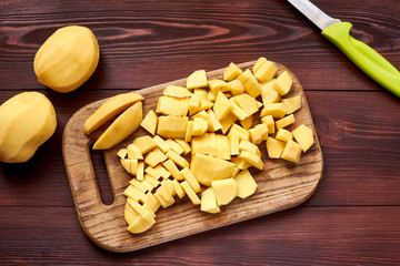 peeled sliced raw potatoes on a wooden board. Preparing vegetables for cooking.