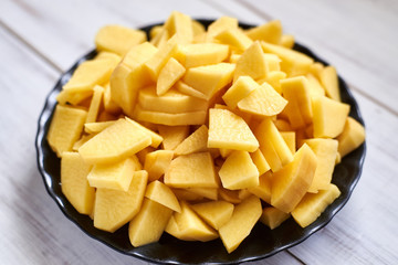 peeled sliced raw potatoes on a wooden board. Preparing vegetables for cooking.