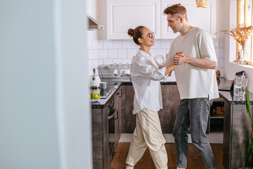 beautiful caucasian married couple dancing in the kitchen at home, happy couple having fun, enjoy...