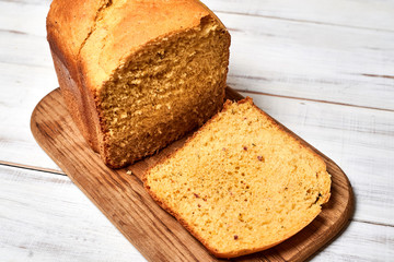 A loaf of baked homemade bread on a white wooden background.