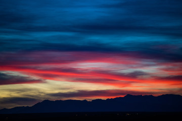 Obraz premium A stunning sunset or sunrise scene of silhouette mountain peaks and purple ridges with the twilight background, the blue sky and the pink-yellow skyline
