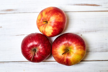Ripe red apples on a wooden background.