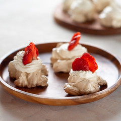 the process of creating Pavlova dessert, decorating the meringue with strawberries