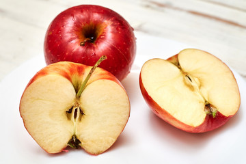 Ripe red apples on a plate on a wooden background.