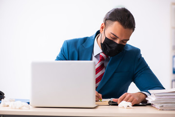 Sick male employee suffering at workplace from coronavirus