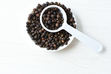 Whole and ground black peppercorns on white wooden background