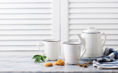 Tea in mugs with teapot on marble background. Copy space.