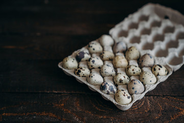 Quail eggs in craft paper box on dark wooden background.  farm products, organic products, Healthy food concept