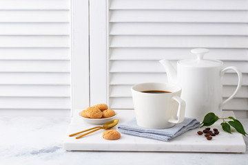 Black coffee in mugs with coffee pot on marble cutting board. White background. Copy space.