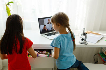 Cool online school. Kids studying online at home using a laptop. Cheerful young little girls using laptop computer studying through online e-learning system. Distance or remote learning