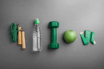 Attributes of a healthy lifestyle. Fruit, green dumbbell, water bottle, ruler, rope, on a neutral background. Counting calories. The diet plan. View from above. Close-up. Minimalism.