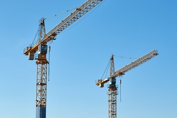 Construction site tower cranes against clear blue sky