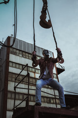 a young man in a factory during the Apocalypse in a castle and with a saw