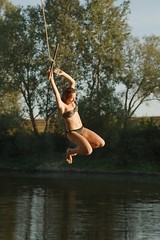 Young woman on a rope swing by the river