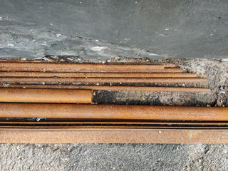 Rusty, old pipes of different diameters lie near the wall, like waste rubbish and scrap. Photography, concept.