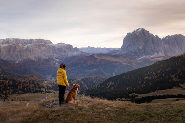 Naklejka premium person with a dog in the mountains. travel, hiking with a pet. Nova Scotia retriever with a girl.