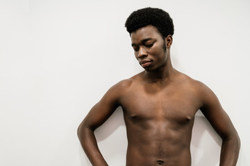 Portrait of a muscular African man posing in a photo studio with a white nude background without a T-shirt