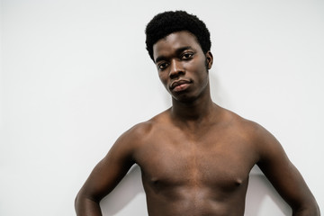 Portrait of a muscular African man posing in a photo studio with a white nude background without a T-shirt