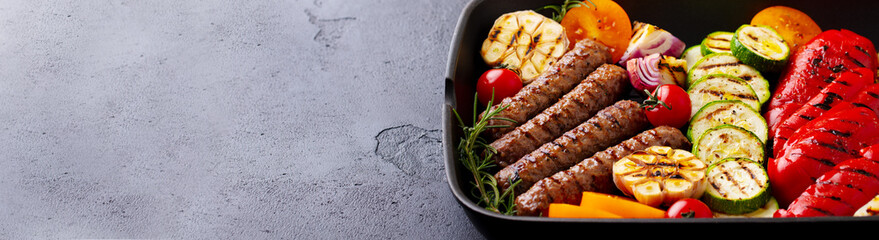 Grilled meat kebab and vegetables in grill pan. Black background. Close up. Copy space.