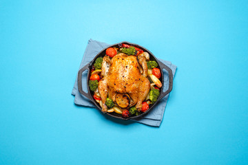 Roasted chicken with vegetables in an iron cast, top view.