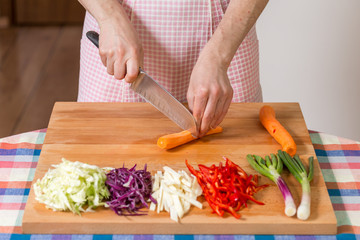 Close up of hands chopping carrots on a wooden board...Healthy food preparation concept