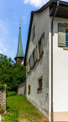 Medieval bell tower of a small village church in the Swiss Alps  among the trees and meadows