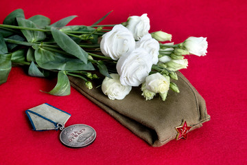 Victory Day May 9 postcard concept with old soviet medal "For bravery", flowers and military cap