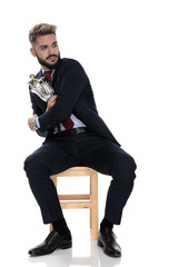young businessman in suit looking to side and protecting trophy