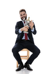 Fototapeta premium proud businessman smiling and presenting trophy