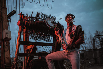 a young man in a factory during the Apocalypse in a castle and with a saw