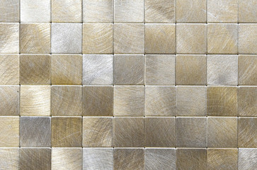 Metal mosaic tile with golden and silvery squares.