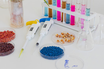 Herbicide-treated corn, suflowers, chick-pea seeds in a Petri dish and sprouted seeds on a table with a dispenser and test tubes