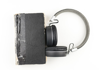 Audio book concept. headphones with book on white background. Listening to book. Modern education. Copyspace.