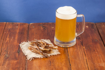 Dried fish in the shape of a straw with beer glass on wooden table. Salted fish delicacies on a...