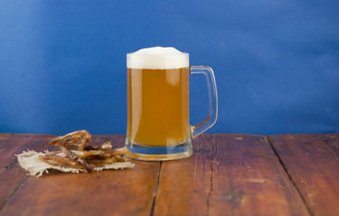 Dried fish in the shape of a straw with beer glass on wooden table. Salted fish delicacies on a table. Close-up.