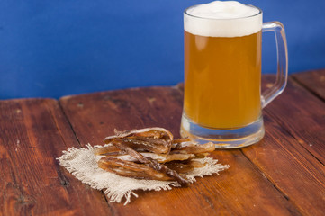 Dried fish in the shape of a straw with beer glass on wooden table. Salted fish delicacies on a...