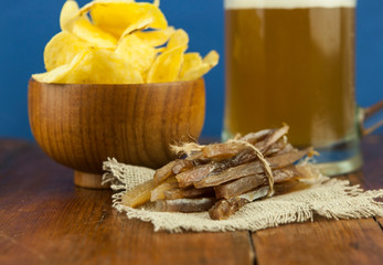 Beer glass with beer and smoked fish close-up. Beer mug with beer and potato chips, crackers on a wood background and copy space.