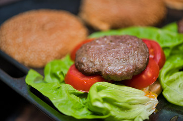 Tasty hamburger prepared on the table, closeup of tomatoes and meat
