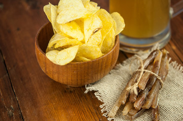 Beer glass with beer and smoked fish close-up. Beer mug with beer and potato chips, crackers on a wood background and copy space.