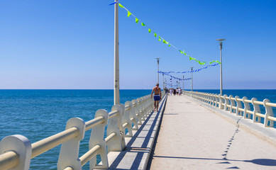 Obraz premium View of the pier of Forte dei Marmi with vacationers in a sunny summer day, Versilia coast, Tuscany, Italy