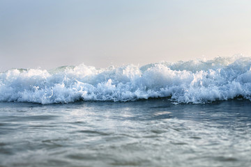 sea wave with splashes surges to the beach, against the sky